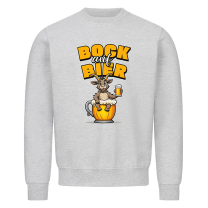 Grauer Sweater mit Rundhalsausschnitt. Auf der Vorderseite ist ein stilisierter, brauner Ziegenbock mit einem gelben Bierkrug in der Hand abgebildet. Der Bock sitzt in einer großen, goldenen Bierkrug-Silhouette. Über dem Bock steht der Schriftzug "BOCK auf BIER", wobei "BOCK" und "BIER" in gelber Farbe und "auf" in weißer Farbe dargestellt ist.