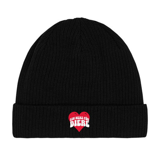 Schwarzer Beanie mit einem roten Herz in der Mitte. Darauf steht in verspielten, weißen Buchstaben „EIN HERZ FÜR BIERE“. Das Design ist humorvoll und spielt auf die bekannte Redewendung „Ein Herz für …“ an, kombiniert mit einer Liebe zu Bier.